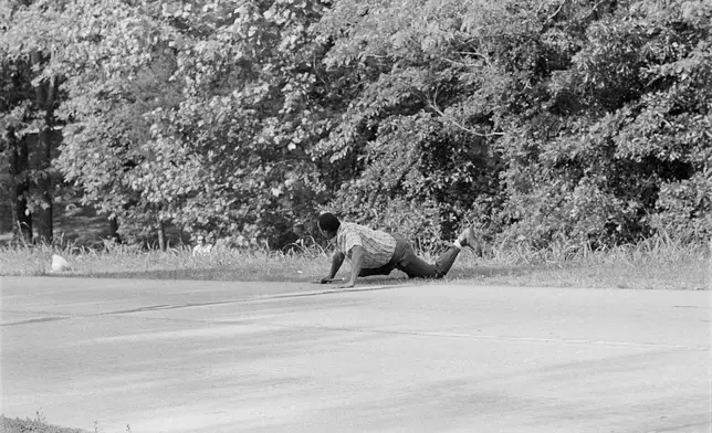 FILE - James Meredith looks at Aubrey James Norvell, background left partially hidden behind foliage, after being shot on a road near Hernando, Miss., June 6, 1966. (AP Photo/Jack Thornell, File)