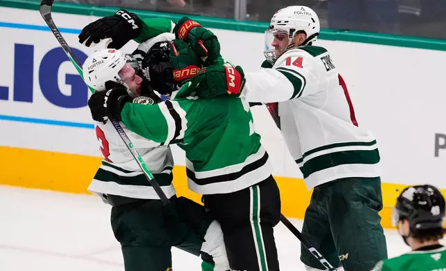 Minnesota Wild's Quinn Hughes, left, Dallas Stars' Mikko Rantanen, center, and Joel Eriksson Ek (14) fight in the third period of an NHL hockey game Thursday, April 9, 2026, in Arlington, Texas. (AP Photo/Tony Gutierrez)