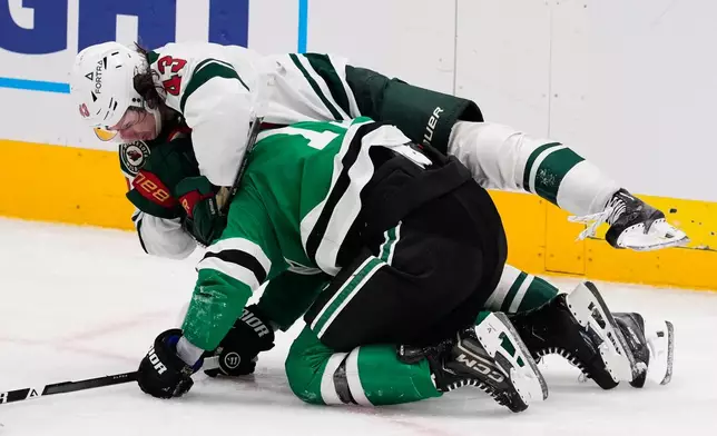 Minnesota Wild defenseman Quinn Hughes, top and Dallas Stars' Adam Erne (73) fight in the third period of an NHL hockey game Thursday, April 9, 2026, in Arlington, Texas. (AP Photo/Tony Gutierrez)