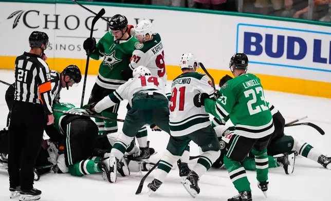 Referee TJ Luxmore (21) looks on as fights break out between the Dallas Stars and Minnesota Wild in the third period of an NHL hockey game Thursday, April 9, 2026, in Arlington, Texas. (AP Photo/Tony Gutierrez)