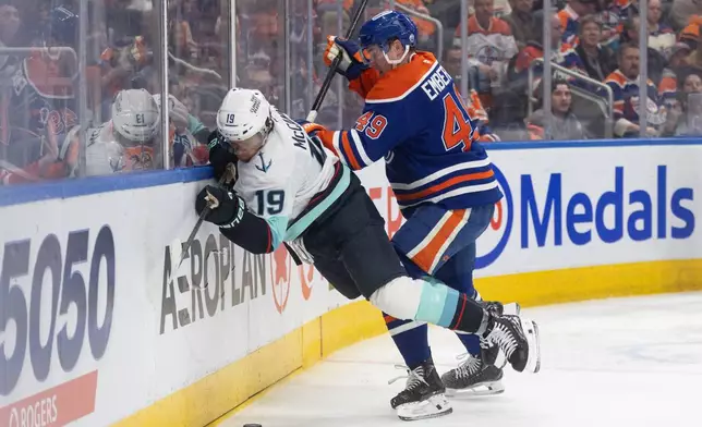 Seattle Kraken's Jared McCann (19) is checked by Edmonton Oilers' Ty Emberson (49) during third period NHL action, in Edmonton on Tuesday March 31, 2026. (Jason Franson/The Canadian Press via AP)
