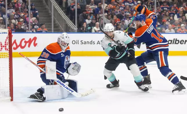 Edmonton Oilers goalie Connor Ingram (39) makes the save as Seattle Kraken's Jordan Eberle (7) and Mattias Ekholm (14) battle for the rebound during first period NHL action, in Edmonton on Tuesday, March 31, 2026. (Jason Franson/The Canadian Press via AP)