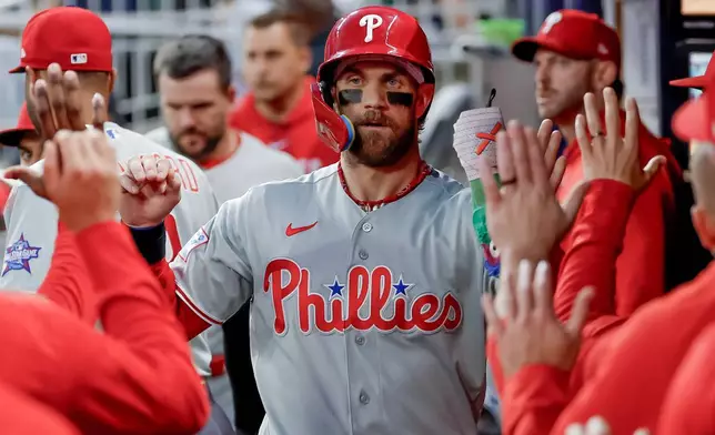 Philadelphia Phillies' Bryce Harper is greeted in the dugout after scoring against the Atlanta Braves during the first inning of a baseball game, Saturday, April 25, 2026, in Atlanta. (AP Photo/Erik S. Lesser)