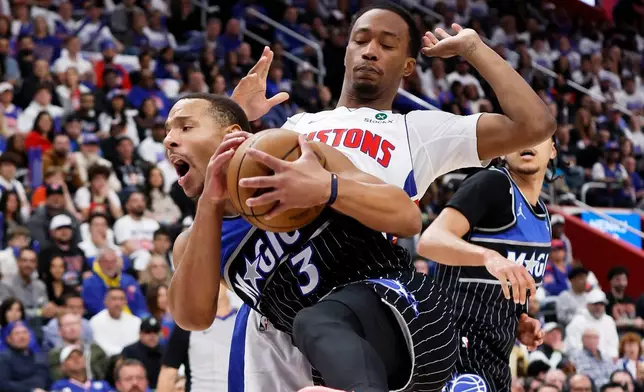 Orlando Magic guard Desmond Bane (3) grabs a rebound in front of Detroit Pistons forward Ronald Holland II, top right, during the first half in Game 1 of a first-round NBA basketball playoffs series Sunday, April 19, 2026, in Detroit. (AP Photo/Duane Burleson)