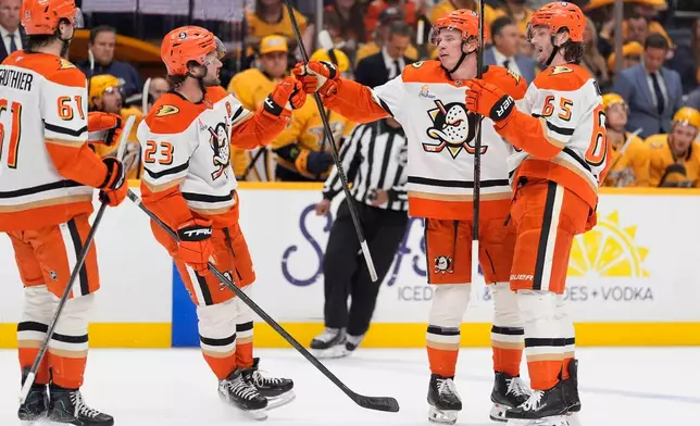 Anaheim Ducks defenseman Jackson LaCombe, second from right, celebrates his goal with left wing Cutter Gauthier (61), center Mason McTavish (23) and defenseman Jacob Trouba (65) during the first period of an NHL hockey game against the Nashville Predators, Thursday, April 16, 2026, in Nashville, Tenn. (AP Photo/George Walker IV)