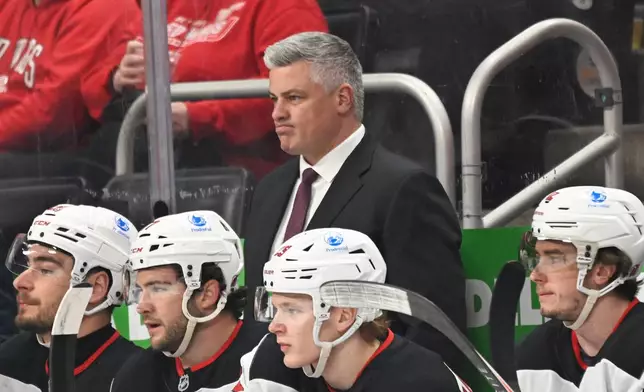 New Jersey Devils head coach Sheldon Keefe, center top, watches the first period of an NHL hockey game against the Detroit Red Wings, Saturday, April 11, 2026, in Detroit. (AP Photo/Jose Juarez)