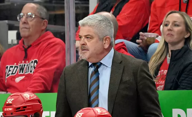Detroit Red Wings head coach Todd McLellan, center, watches the first period of an NHL hockey game against the New Jersey Devils, Saturday, April 11, 2026, in Detroit. (AP Photo/Jose Juarez)