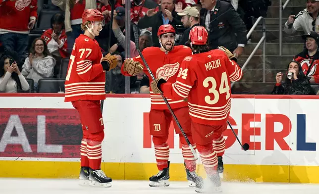 Detroit Red Wings left wing David Perron, middle, is congratulated by defenseman Simon Edvinsson, left, and left wing Carter Mazur during the second period of an NHL hockey game, Saturday, April 11, 2026, in Detroit. (AP Photo/Jose Juarez)