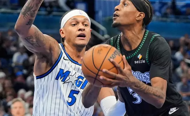 Minnesota Timberwolves forward Jaden McDaniels, right, shoots against Orlando Magic forward Paolo Banchero (5) during the first half of an NBA basketball game, Wednesday, April 8, 2026, in Orlando, Fla. (AP Photo/John Raoux)