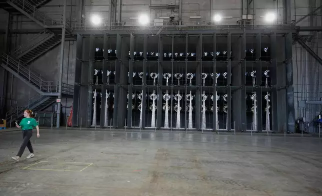 A person walks near fans used for wildfire research at the Institute for Business &amp; Home Safety center on Thursday, April 16, 2026, in Richburg, S.C. (AP Photo/Erik Verduzco)