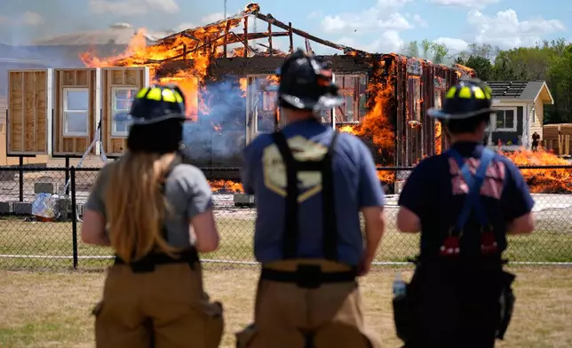 Chester County Firefighters Elizabeth Stevenson, from left, Michael Mackey and Charles Lee, watch an accessory dwelling unit burn during an experiment at the Institute for Business &amp; Home Safety center Wednesday, April 1, 2026, in Richburg, S.C. (AP Photo/Erik Verduzco)