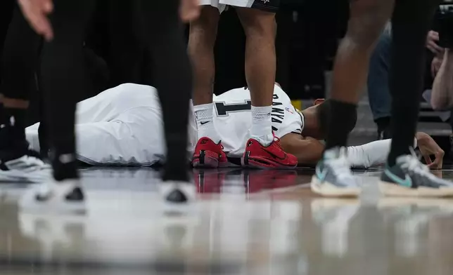 San Antonio Spurs forward Victor Wembanyama (1) lies on the court after a hard fall during the first half in Game 2 of a first-round NBA playoffs basketball series against the Portland Trail Blazers in San Antonio, Tuesday, April 21, 2026. (AP Photo/Eric Gay)