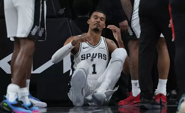 San Antonio Spurs forward Victor Wembanyama (1) sits on the court after a hard fall during the first half in Game 2 of a first-round NBA playoffs basketball series against the Portland Trail Blazers in San Antonio, Tuesday, April 21, 2026. (AP Photo/Eric Gay)