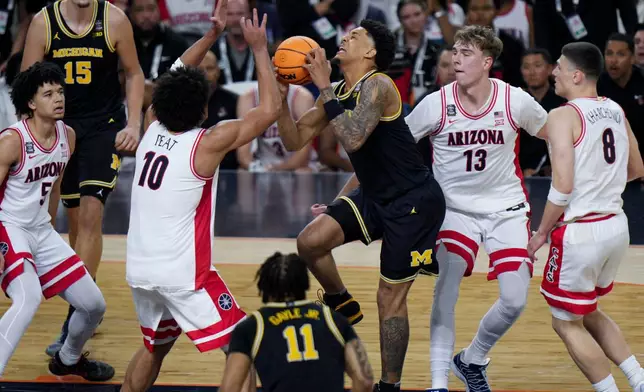 Michigan forward Yaxel Lendeborg, center, is injured on a play as Arizona center Motiejus Krivas (13) and forward Koa Peat (10) defend during the first half of an NCAA college basketball tournament semifinal game against Arizona at the Final Four, Saturday, April 4, 2026, in Indianapolis. (AP Photo/AJ Mast)
