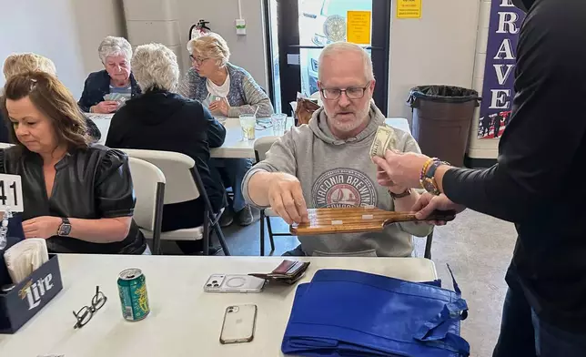 Minnesota state Rep. Jim Nash, R-Waconia, right, buys tickets for the weekly meat raffle April 10, 2026, at American Legion Post 150 in Waconia, Minn. (AP Photo/Steve Karnowski)