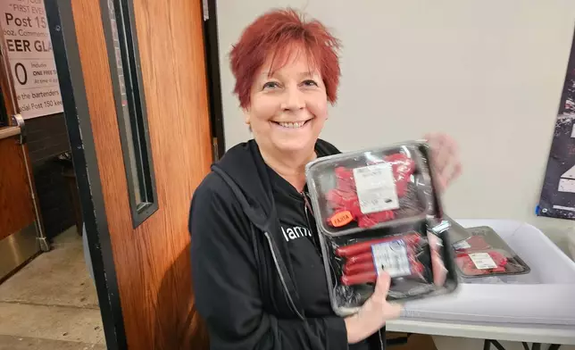 Andrea "Mama" Avaloz holds up the package of fajita meat, beef sticks and pork chops that she won in a meat raffle April 10, 2026, at American Legion Post 150 in Waconia, Minn. (AP Photo/Steve Karnowski)