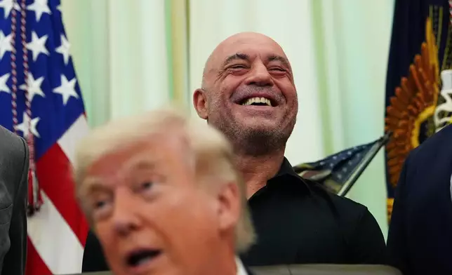 Joe Rogan laughs as President Donald Trump speaks in the Oval Office of the White House, Saturday, April 18, 2026, in Washington. (AP Photo/Julia Demaree Nikhinson)