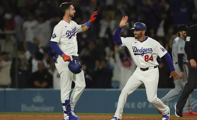 Los Angeles Dodgers' Kyle Tucker, left, celebrates with first base coach Chris Woodward after hitting a walk off single during the ninth inning of a baseball game against the Miami Marlins Monday, April 27, 2026, in Los Angeles. (AP Photo/Ryan Sun)