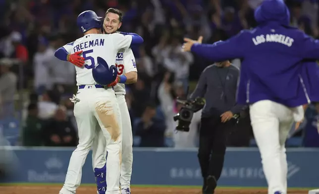 Los Angeles Dodgers' Kyle Tucker, center, celebrates with Freddie Freeman, left, after hitting a walk off single during the ninth inning of a baseball game against the Miami Marlins Monday, April 27, 2026, in Los Angeles. (AP Photo/Ryan Sun)