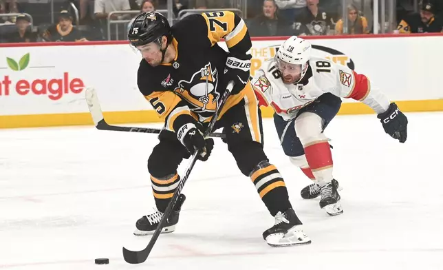 Pittsburgh Penguins defenseman Connor Clifton (75) moves the puck under pressure from Florida Panthers left wing Noah Gregor (18) during the second period of an NHL game, Saturday, April 4, 2026, in Pittsburgh. (AP Photo/Philip G. Pavely)