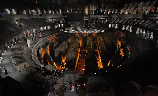 Pope Leo XIV carries a lightweight, 1.5-meter (5-foot) wooden cross during the Via Crucis, the torchlit Good Friday Stations of the Cross procession at the Colosseum in Rome, Friday, April 3, 2026, which symbolically retraces Jesus Christ's steps to his crucifixion on Calvary in Jerusalem. (AP Photo/Alessandra Tarantino)
