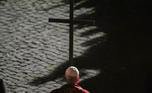 Pope Leo XIV carries a lightweight, 1.5-meter (5-foot) wooden cross during the Via Crucis, the torchlit Good Friday Stations of the Cross procession at the Colosseum in Rome, Friday, April 3, 2026, which symbolically retraces Jesus Christ's steps to his crucifixion on Calvary in Jerusalem. (AP Photo/Alessandra Tarantino)