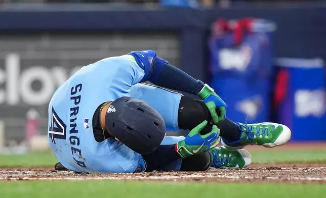 Toronto Blue Jays designated hitter George Springer falls to the ground after taking a foul ball off his foot while playing against the Minnesota Twins during third-inning baseball game action in Toronto, Saturday, April 11, 2026. (Nathan Denette/The Canadian Press via AP)