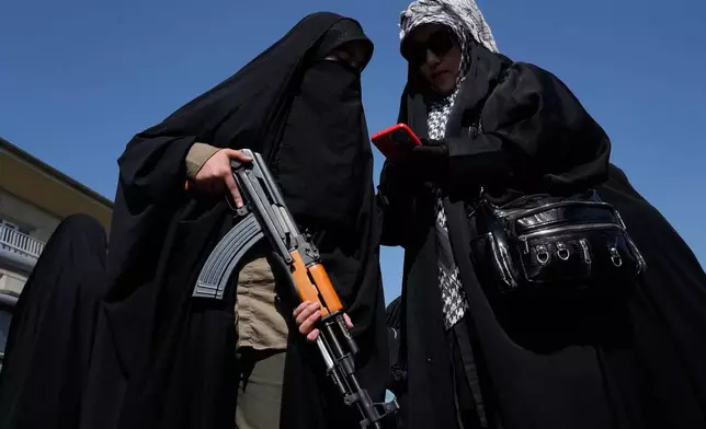 A woman member of the Basij paramilitary, affiliated with Iran's Revolutionary Guard, holds her gun during a state-organized rally in support of the supreme leader marking National Girl's Day in Tehran, Iran, Friday, April 17, 2026. (AP Photo/Vahid Salemi)