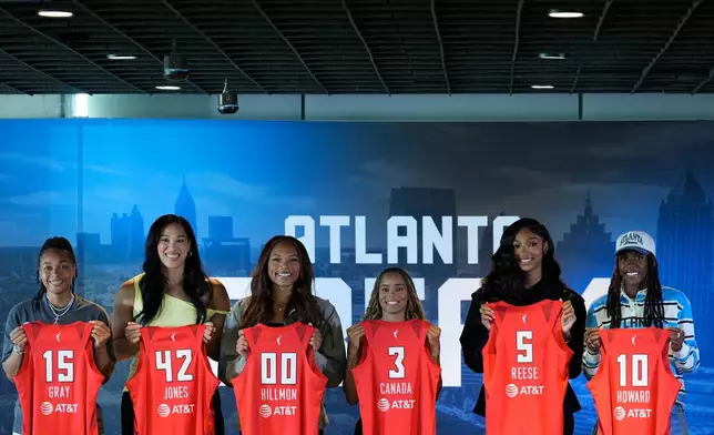 Atlanta Dream's Allisha Gray, Brionna Jones, Naz Hillmon, Jordin Canada, Angel Reese And Rhyne Howard hold up their jerseys during a news conference by the Atlanta Dream on Friday, April 17, 2026, in Atlanta. (AP Photo/Brynn Anderson)