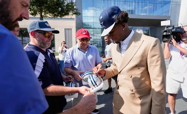 Dallas Cowboys first-round draft pick Caleb Downs, front right, gives autographs to fans as he departs from the team's NFL football headquarters Friday, April 24, 2026, in Frisco, Texas. (AP Photo/Tony Gutierrez)