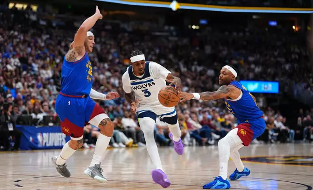 Minnesota Timberwolves forward Jaden McDaniels (3) drives to the basket against Denver Nuggets forward Aaron Gordon (32) and Bruce Brown (11) during the second half in Game 2 of a first-round NBA playoffs basketball series Monday, April 20, 2026, in Denver. (AP Photo/Jack Dempsey)