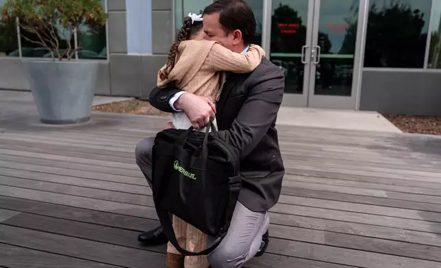 FILE - Milenko Faria, whose wife, Dr. Rubeliz Bolivar, is in immigration custody, hugs their daughter, Milena, after his asylum interview at the U.S. Citizenship and Immigration Services facility in Tustin, Calif., Thursday, April 16, 2026. (AP Photo/Jae C. Hong, File)