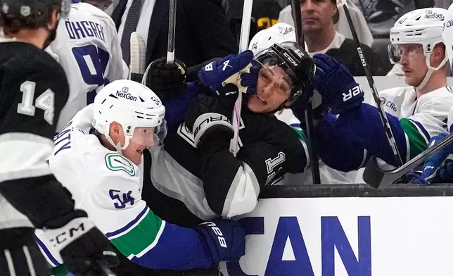 Vancouver Canucks center Aatu Räty, left, puts Los Angeles Kings left wing Trevor Moore into the boards during the first period of an NHL hockey game Thursday, April 9, 2026, in Los Angeles. (AP Photo/Mark J. Terrill)