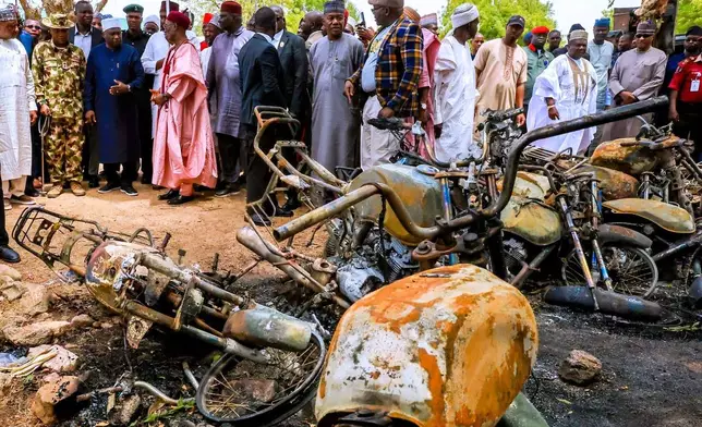 In this photo, released by Adamawa State Government House, Adamawa State Governor Ahmadu Umaru Fintiri, left white hat, inspects an area in Guyaku, northeastern Nigeria, Monday, April 27, 2026, that was attacked by Militants with the Islamic State group on Sunday. (Adamawa state government house via AP)