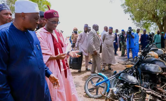 In this photo, released by Adamawa State Government House, Adamawa State Governor Ahmadu Umaru Fintiri, front left, inspects an area in Guyaku, northeastern Nigeria, Monday, April 27, 2026, that was attacked by Militants with the Islamic State group on Sunday. (Adamawa state government house via AP)