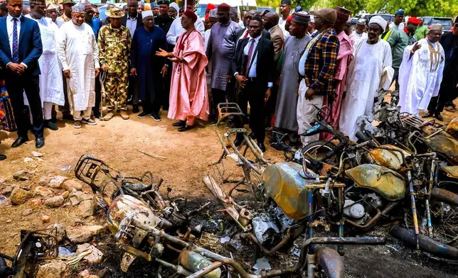 In this photo, released by Adamawa State Government House, Adamawa State Governor Ahmadu Umaru Fintiri, center left white hat, inspects an area in Guyaku, northeastern Nigeria, Monday, April 27, 2026, that was attacked by Militants with the Islamic State group on Sunday. (Adamawa state government house via AP)