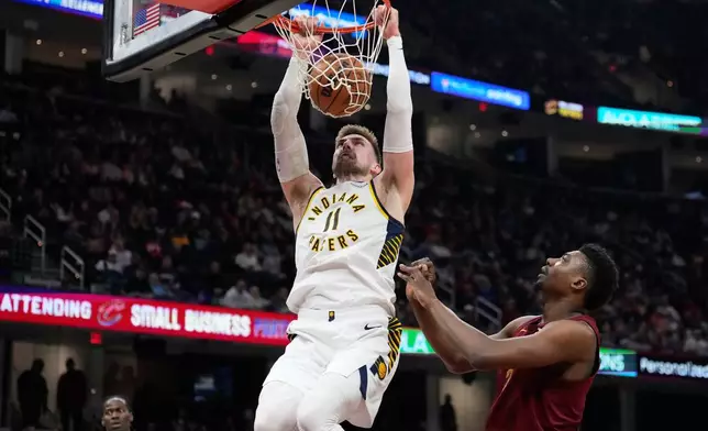 Indiana Pacers center Micah Potter (11) dunks next to Cleveland Cavaliers center Thomas Bryant, right, in the first half of an NBA basketball game in Cleveland, Sunday, April 5, 2026. (AP Photo/Sue Ogrocki)