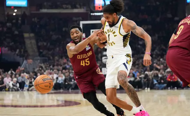 Cleveland Cavaliers guard Donovan Mitchell (45) knocks the ball away from Indiana Pacers forward Obi Toppin (1) in the first half of an NBA basketball game in Cleveland, Sunday, April 5, 2026. (AP Photo/Sue Ogrocki)