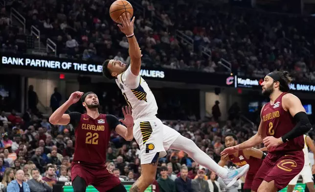 Indiana Pacers forward Jalen Slawson, center, grabs a pass between Cleveland Cavaliers forward Larry Nance Jr. (22) and guard Max Strus, right, in the first half of an NBA basketball game in Cleveland, Sunday, April 5, 2026. (AP Photo/Sue Ogrocki)