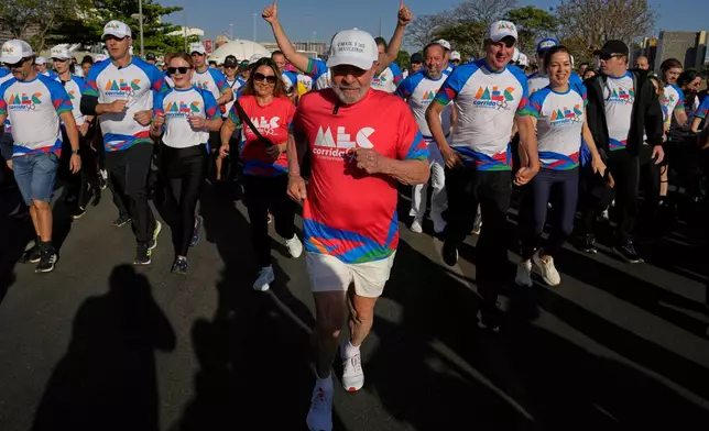 FILE - Brazil's President Luiz Inacio Lula da Silva, center, and first lady Rosangela da Silva, front left in a red jersey, take part in the 'Walk in Celebration' to mark the Ministry of Culture's 95th anniversary, in Brasilia, Brazil, Sept. 28, 2025. (AP Photo/Eraldo Peres, File)