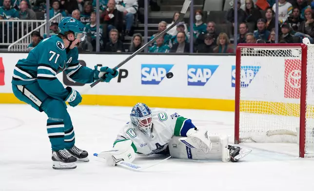 Vancouver Canucks goaltender Kevin Lankinen, right, blocks a shot by San Jose Sharks center Macklin Celebrini (71) during the first period of an NHL hockey game in San Jose, Calif., Saturday, April 11, 2026. (AP Photo/Tony Avelar)