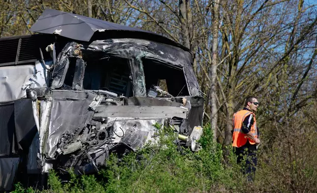A railway worker stands near a high-speed train (TGV) after he crashed into a truck carrying military equipment in Bully-les-Mines, northern France, Tuesday, April 7, 2026. (AP Photo/Jean-Francois Badias)