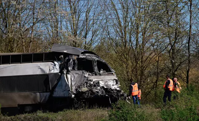Railway workers stand near a high-speed train(TGV) after he crashed into a truck carrying military equipment in Bully-les-Mines, northern France, Tuesday, April 7, 2026. (AP Photo/Jean-Francois Badias)
