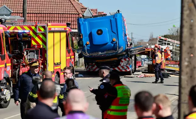 Rail workers and policemen stand near the truck carrying military equipment after the crash against a high-speed train (TGV) in Bully-les-Mines, northern France, Tuesday, April 7, 2026. (AP Photo/Jean-Francois Badias)