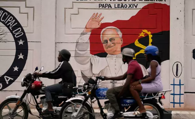 People traveling on a motorcycles ride past a mural featuring Pope Leo XIV, in Luanda, South Africa, Thursday, April 16, 2026. (AP Photo/Themba Hadebe)