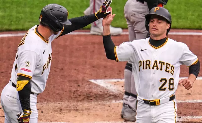 Pittsburgh Pirates' Jake Mangum (28) high-fives teammate Ryan O'Hearn after scoring a run during the second inning of a baseball game in Pittsburgh, Sunday, April 5, 2026. (AP Photo/Gene J. Puskar)