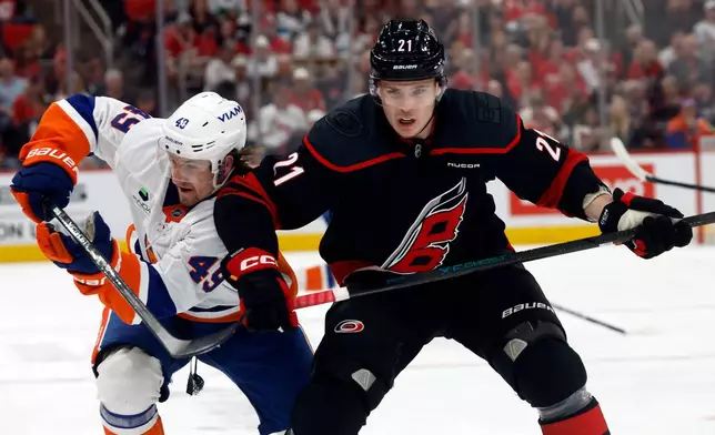 Carolina Hurricanes' Alexander Nikishin (21) battles for position with New York Islanders' Max Shabanov (49) uring the first period of an NHL hockey game in Raleigh, N.C., Saturday, April 4, 2026. (AP Photo/Karl DeBlaker)