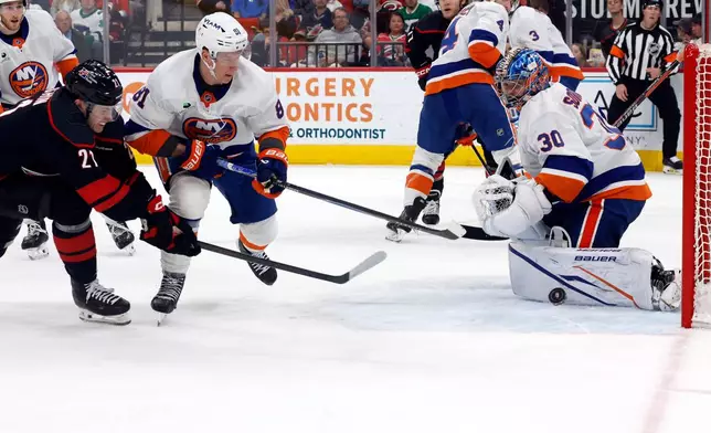 Carolina Hurricanes' Alexander Nikishin (21) has his shot go off the pad of New York Islanders goaltender Ilya Sorokin (30) with Ondrej Palat (81) nearby during the second period of an NHL hockey game in Raleigh, N.C., Saturday, April 4, 2026. (AP Photo/Karl DeBlaker)
