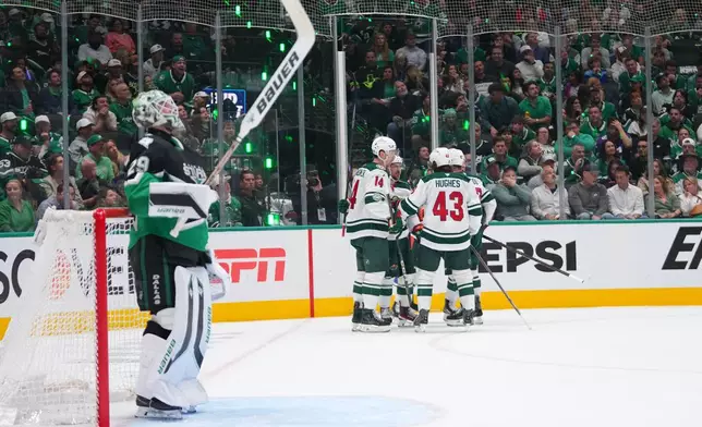 Dallas Stars goaltender Jake Oettinger, left, looks on as Minnesota Wild players celebrate a second period power play goal by left wing Matt Boldy, back right, in Game 5 of a first-round NHL Stanley Cup playoffs hockey series, Tuesday, April 28, 2026, in Dallas. (AP Photo/Julio Cortez)