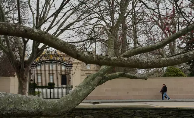 People walk near a mansion and a red maple tree Wednesday, April 22, 2026, in Newport, R.I. (AP Photo/Joshua A. Bickel)